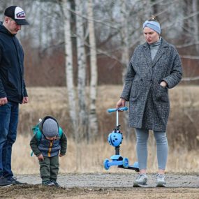 Family spending time outdoors with a scooter in autumn park setting.
